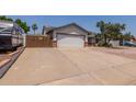 Wide driveway accessing the two-car garage and RV parking behind a wood fence with brick trim at 6110 E Ivyglen St, Mesa, AZ 85205
