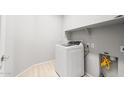 A laundry room with washer, storage shelf, and light wood flooring at 26992 W Melinda Ln, Buckeye, AZ 85396