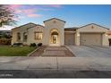 Inviting front exterior featuring an arched entryway, a two-car garage, and green landscaping at 3574 E Tonto Pl, Chandler, AZ 85249