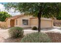 Tan-colored home with a two-car garage, desert landscaping, and covered porch at 10317 E Kiva Cir, Mesa, AZ 85209
