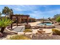 Outdoor oasis featuring a pergola, built-in grill, fire pit, and a sparkling pool at 14188 W Hope Dr, Surprise, AZ 85379
