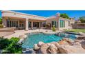Resort-style pool featuring rock accents, mature landscaping, and an expansive patio with an outdoor dining area at 16441 S Mountain Stone Trl, Phoenix, AZ 85048