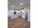 Modern kitchen with white cabinets, stainless steel appliances, a kitchen island and wood-look flooring at 18225 W Larkspur Dr, Goodyear, AZ 85338