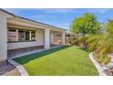 Inviting backyard with lush artificial turf, mature tree, and a covered patio area at 22472 E Sonoqui Blvd, Queen Creek, AZ 85142