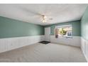 Bright living room with neutral carpet, decorative chair railing, ceiling fan, and large window for natural light at 8020 E Keats Ave # 285, Mesa, AZ 85209