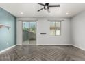 Bright living room features stylish gray herringbone floors, a ceiling fan, sliding glass door, and white trim at 1056 N Miller Rd, Tempe, AZ 85288