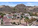 Luxury estate with a circular driveway, desert landscaping, and palm trees against a mountain backdrop at 11809 S Montezuma Ct, Phoenix, AZ 85044