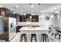 Modern kitchen features dark cabinets, stainless steel appliances, a granite island with seating and pendant lights at 12690 S 184Th Ave, Goodyear, AZ 85338