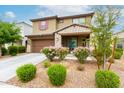 This two-story home features a stone-accented facade, a two-car garage, and vibrant flowering bushes at 17424 W Willow Ave, Surprise, AZ 85388