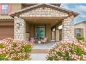 Cozy front porch with stone pillars, outdoor seating, and flowering bushes create a welcoming entrance at 17424 W Willow Ave, Surprise, AZ 85388