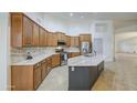 Spacious kitchen with light countertops, stainless steel appliances, a stylish island, and ample wooden cabinetry at 18249 W Mauna Loa Ln, Surprise, AZ 85388