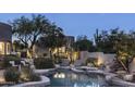Inviting pool with stone accents, lounge chairs, mature trees, and lush landscaping at 26049 N 104Th Pl, Scottsdale, AZ 85255