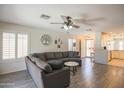 Open-concept living room featuring hardwood floors, a cozy sofa, and seamless flow to the kitchen at 3612 W Charlotte Dr, Glendale, AZ 85310
