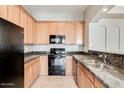 Well-equipped kitchen featuring wood cabinetry, granite countertops, and black appliances at 3820 E Mcdowell Rd # 102, Phoenix, AZ 85008