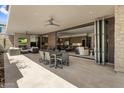 An open patio has an outdoor dining set, fireplace, and living space, seamlessly connecting to the indoor kitchen and living area at 5533 E Stella Ln, Paradise Valley, AZ 85253