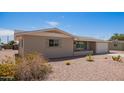 Tan single story home with desert landscaping, a concrete driveway and an attached two car garage at 6043 E Des Moines St, Mesa, AZ 85205