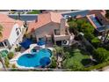 A private backyard oasis featuring a sparkling pool, lush lawn, mature trees and patio with dining set at 7015 W Behrend Dr, Glendale, AZ 85308