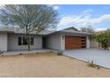 Attractive single story home with a modern wood grain garage door and drought-tolerant landscaping at 8707 E Clarendon Ave, Scottsdale, AZ 85251