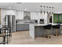 Bright, open kitchen featuring an island, stylish pendant lighting, stainless steel appliances, and modern cabinetry at 8707 E Clarendon Ave, Scottsdale, AZ 85251