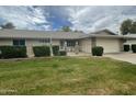 Well-maintained single Gathering house with a green lawn, shrubs, brick accents, and two car garage at 15438 N Lakeforest Dr, Sun City, AZ 85351