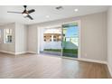 Bright, airy living room with wood flooring, a ceiling fan, and sliding doors to the backyard at 25893 W Running Deer Trl, Wittmann, AZ 85361