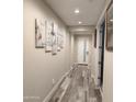 Hallway boasts modern decor, wood-look tile flooring, and recessed lighting, creating a welcoming entrance at 7616 W Jones Ave, Phoenix, AZ 85043