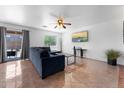 Living room area with tile floors, ceiling fan, sofa, and sliding glass doors at 10939 W Meadowbrook Ave, Phoenix, AZ 85037