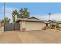 A well-maintained single-story home displaying a large two-car garage and an expansive driveway with desert landscaping at 3215 W Phelps Rd, Phoenix, AZ 85053