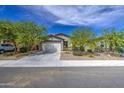 Street view of a single-story home showcasing a two-car garage, desert landscaping, and well-maintained exterior at 33974 N Beeblossom Trl, San Tan Valley, AZ 85144