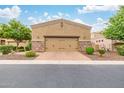 View of the two-car garage featuring a neutral stucco exterior, stone accents, a brick paver driveway, and desert landscaping at 6202 E Mckellips Rd # 189, Mesa, AZ 85215