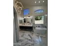 Bright bathroom featuring dual vanity, large soaking tub, marble floors and modern lighting at 6821 W Donald Dr, Glendale, AZ 85310