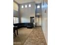 Bright, open-concept living area with high ceilings, a black leather sofa, and tile to carpet flooring at 9108 W Kirby Ave, Tolleson, AZ 85353