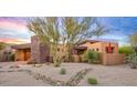 Inviting home with stone accents, desert landscaping, and sunset sky at 9998 E Taos Dr, Scottsdale, AZ 85262