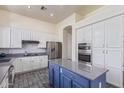 Bright kitchen with white cabinets, stainless steel appliances, and a blue island at 20718 N 58Th Dr, Glendale, AZ 85308