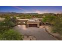 Home exterior showcases desert landscaping, a two-car garage, brick design, and mountain views at dusk at 36223 N 17Th Ave, Phoenix, AZ 85086