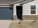 Close-up of the front door with stone veneer and a well maintained yard at 8634 W Albeniz Pl, Tolleson, AZ 85353