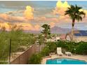 Inviting backyard pool with mountain views, desert landscaping, and stylish lounge chairs; complete with string lights and solar panels at 9628 E Inglewood Cir, Mesa, AZ 85207