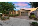 Attractive single-story home with a stone facade, a two-car garage, and a lush, green front yard at 10741 E Palladium Dr, Mesa, AZ 85212