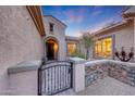 Charming front entrance with an iron gate and stone accent wall, offering privacy and curb appeal at 28770 N 69Th Ln, Peoria, AZ 85383