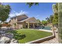 Expansive backyard with pool, patio, artificial turf, and desert landscaping at 6264 E Omega St, Mesa, AZ 85215