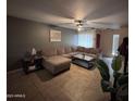 Cozy living room featuring a large sectional sofa, a ceiling fan, and neutral colored walls and floors at 7141 W Denton Ln, Glendale, AZ 85303