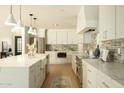 Spacious kitchen features white cabinets, stainless steel appliances, a large island, and modern pendant lighting at 8425 E Welsh Trl, Scottsdale, AZ 85258