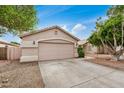Home exterior featuring a well-kept garage, driveway, and drought-resistant landscaping with mature shade trees at 10407 W Reade Ave, Glendale, AZ 85307