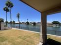 Covered patio offering picturesque waterfront views, with a lawn leading to a fence overlooking the lake at 1414 N Palmsprings Dr, Gilbert, AZ 85234