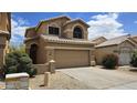 Charming two-story home featuring a two-car garage and desert landscaping with colorful flower bushes under a sunny sky at 1909 N 106Th Ave, Avondale, AZ 85392