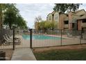 View of a fenced community pool area surrounded by grassy areas and a multi-story condo building at 200 E Southern Ave # 133, Tempe, AZ 85282