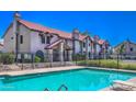 Community pool with lush landscaping and a view of the building's exterior, under a clear, sunny sky at 6262 E Brown Rd # 65, Mesa, AZ 85205