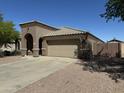 Single story home with tan stucco, tile roof, three car garage, and low maintenance landscaping at 703 E Taylor Trl, San Tan Valley, AZ 85143