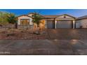 Charming home exterior with a three-car garage, desert landscaping, and inviting curb appeal, providing an instant welcome at 11705 W Luxton Ln, Avondale, AZ 85323