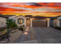 Charming single-story home featuring a landscaped front yard, tiled roof, and a brick-paved driveway at sunset at 26915 W Adam Ave, Buckeye, AZ 85396